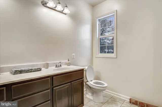 a bathroom with a granite countertop toilet a sink and a window