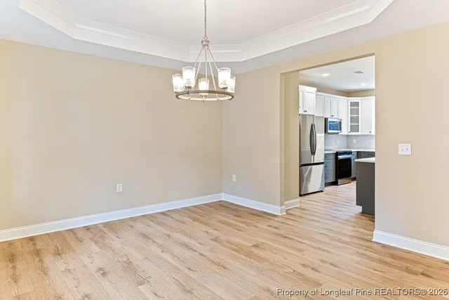 a view of a hallway with wooden floor and a kitchen