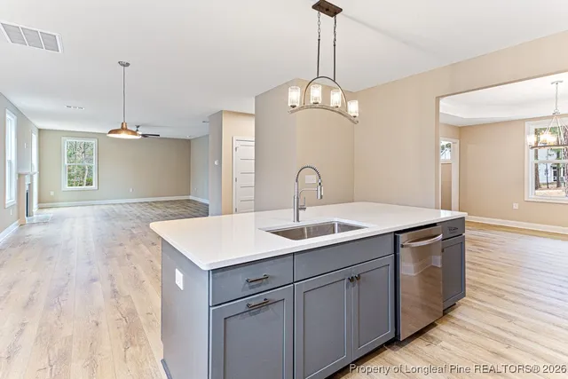 a kitchen with a sink chandelier and wooden floor