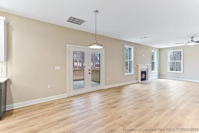 a view of an empty room with window and wooden floor