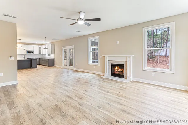 a view of an empty room with a kitchen and fireplace