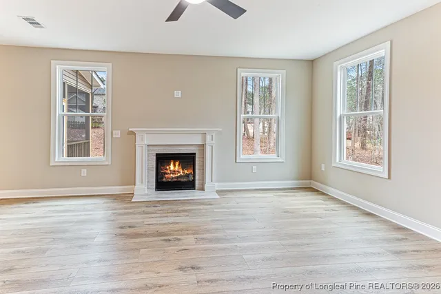 a view of an empty room with wooden floor fireplace and a window