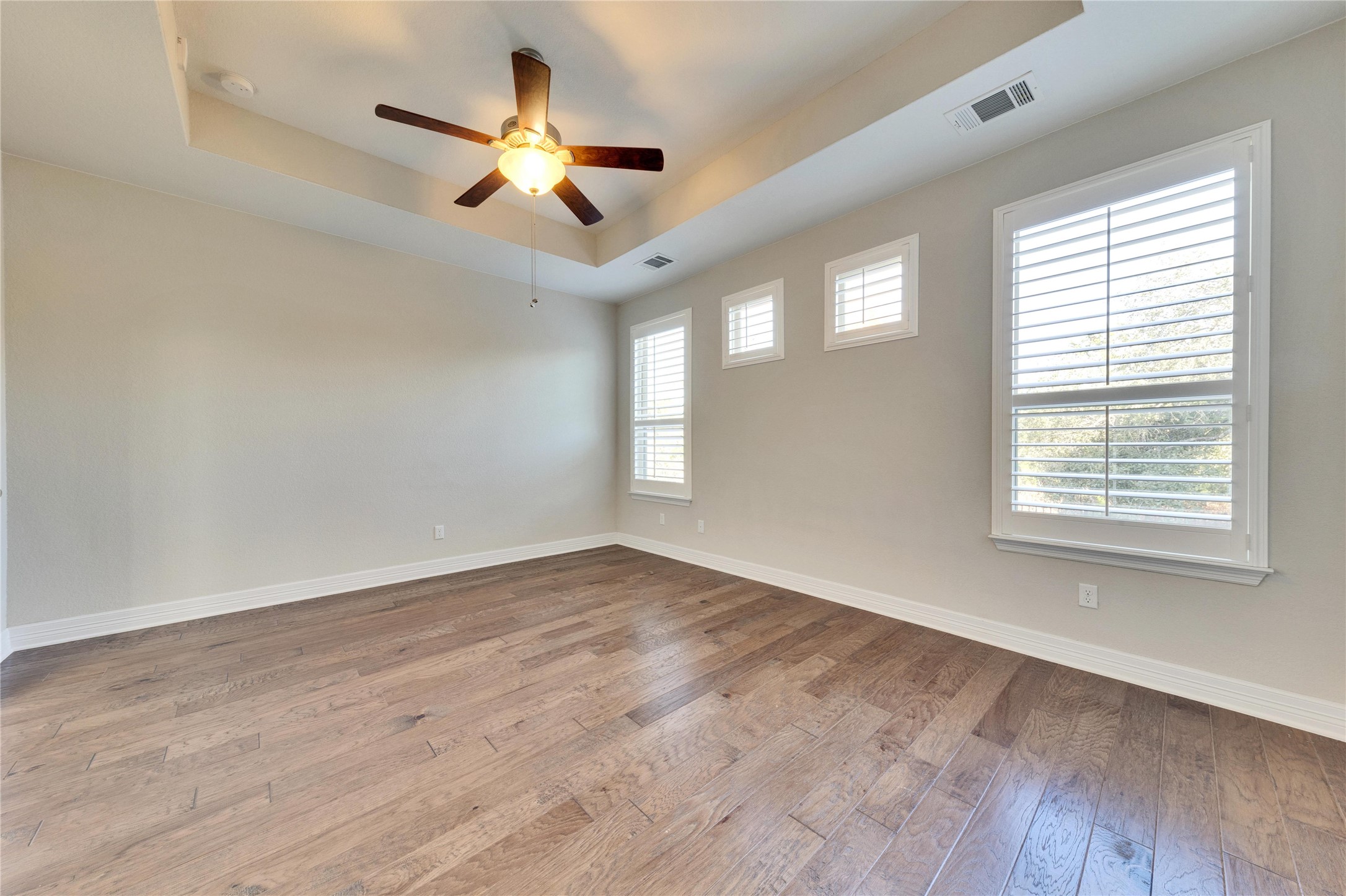 5213 Buchanan Draw Road Austin, TX 78738 - Photo 11 of 33 an empty room with wooden floor ceiling fan and windows