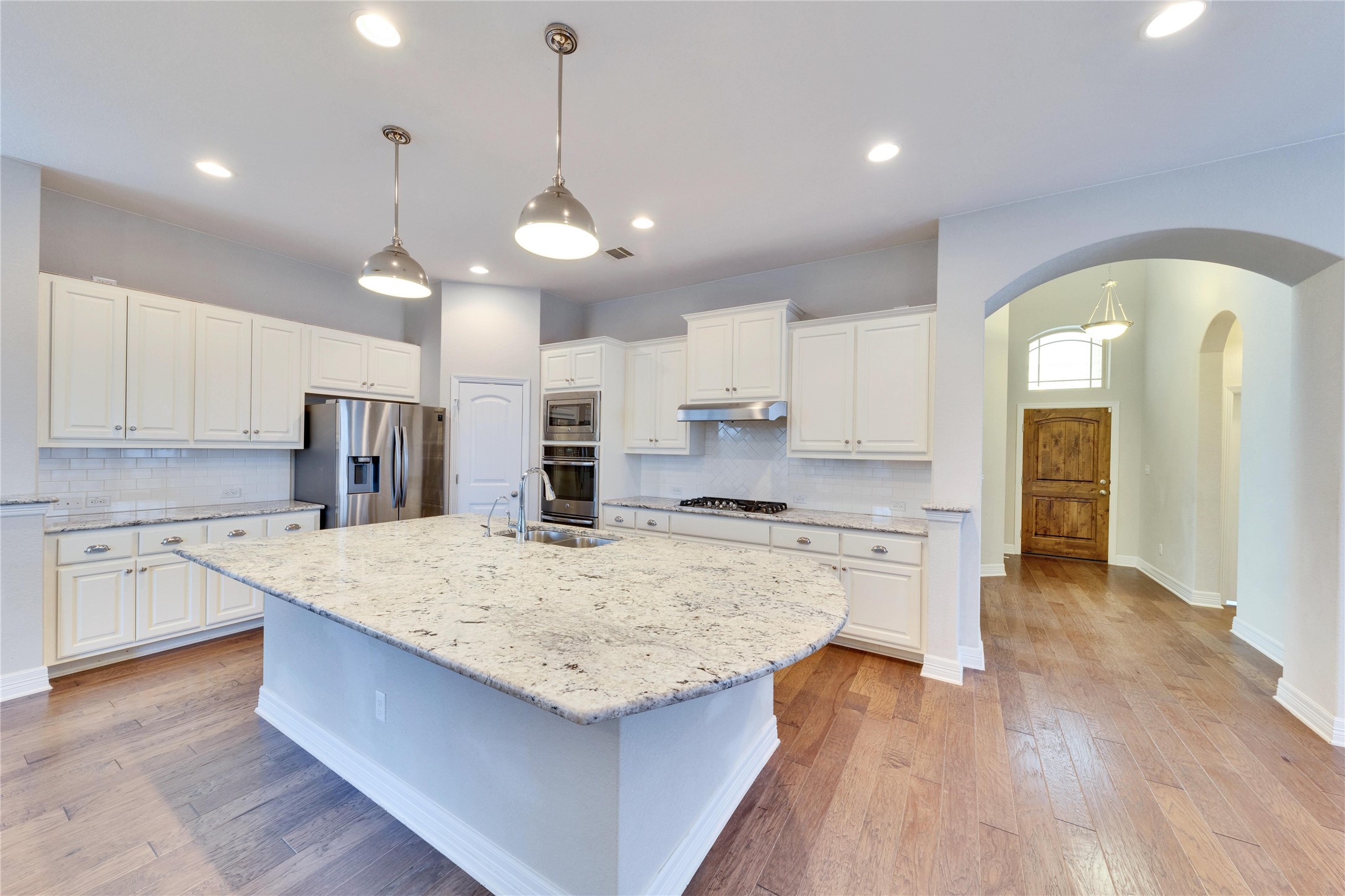 5213 Buchanan Draw Road Austin, TX 78738 - Photo 2 of 33 a large kitchen with kitchen island a stove a sink a center island and wooden floor