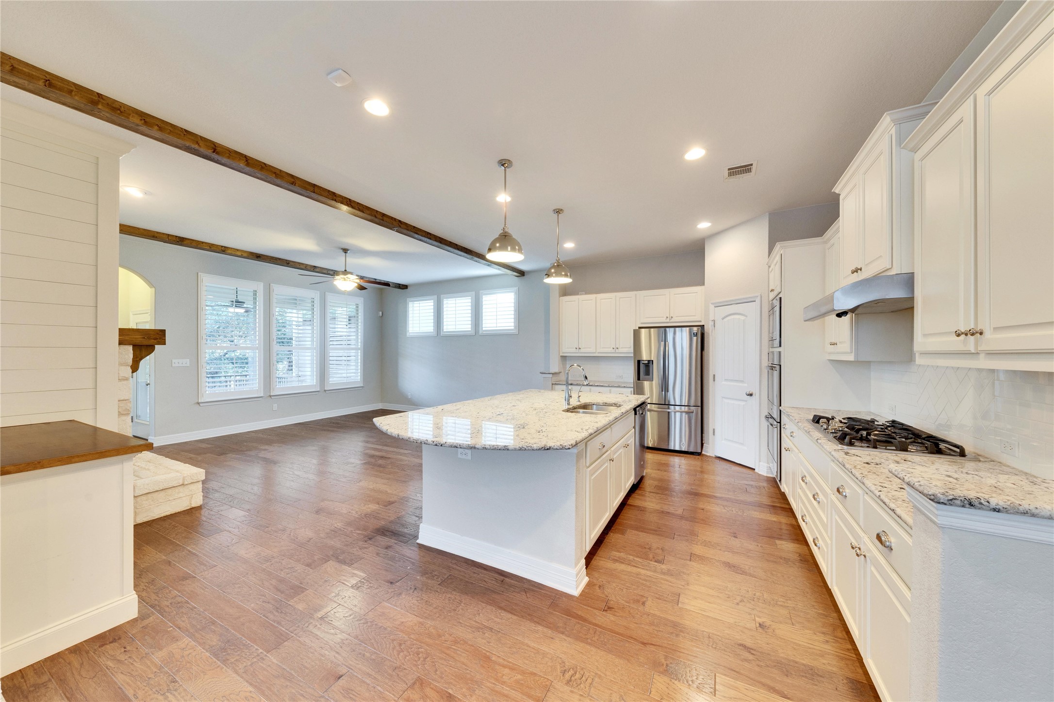 5213 Buchanan Draw Road Austin, TX 78738 - Photo 3 of 33 a large kitchen with kitchen island a stove a sink a refrigerator and white cabinets with wooden floor