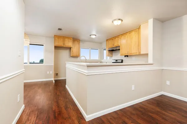 an empty room with wooden floor and windows