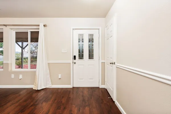 a view of an empty room with a window and wooden floor