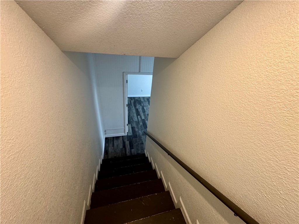 1197 Ridgeview Lane Russellville, AR 72802 - Photo 28 of 44 Stairwell featuring dark-toned treads, a black handrail, and textured wall finishes