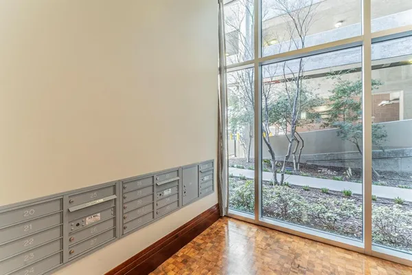 a view of an empty room with wooden floor and a kitchen