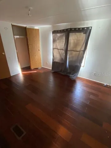 an empty room with wooden floor and cabinet