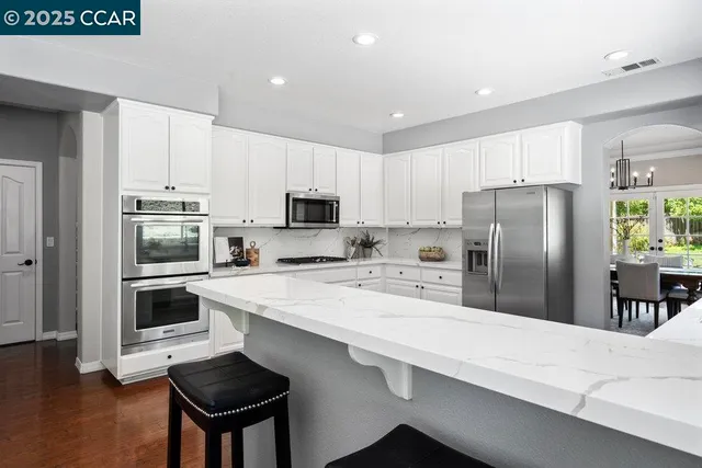 a kitchen with granite countertop white cabinets and white stainless steel appliances