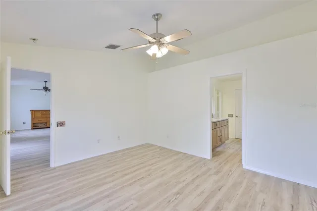 a view of empty room with wooden floor and ceiling fan