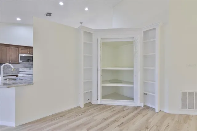 a view of an empty room with wooden floor and closet