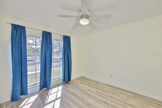 an empty room with windows and ceiling fan