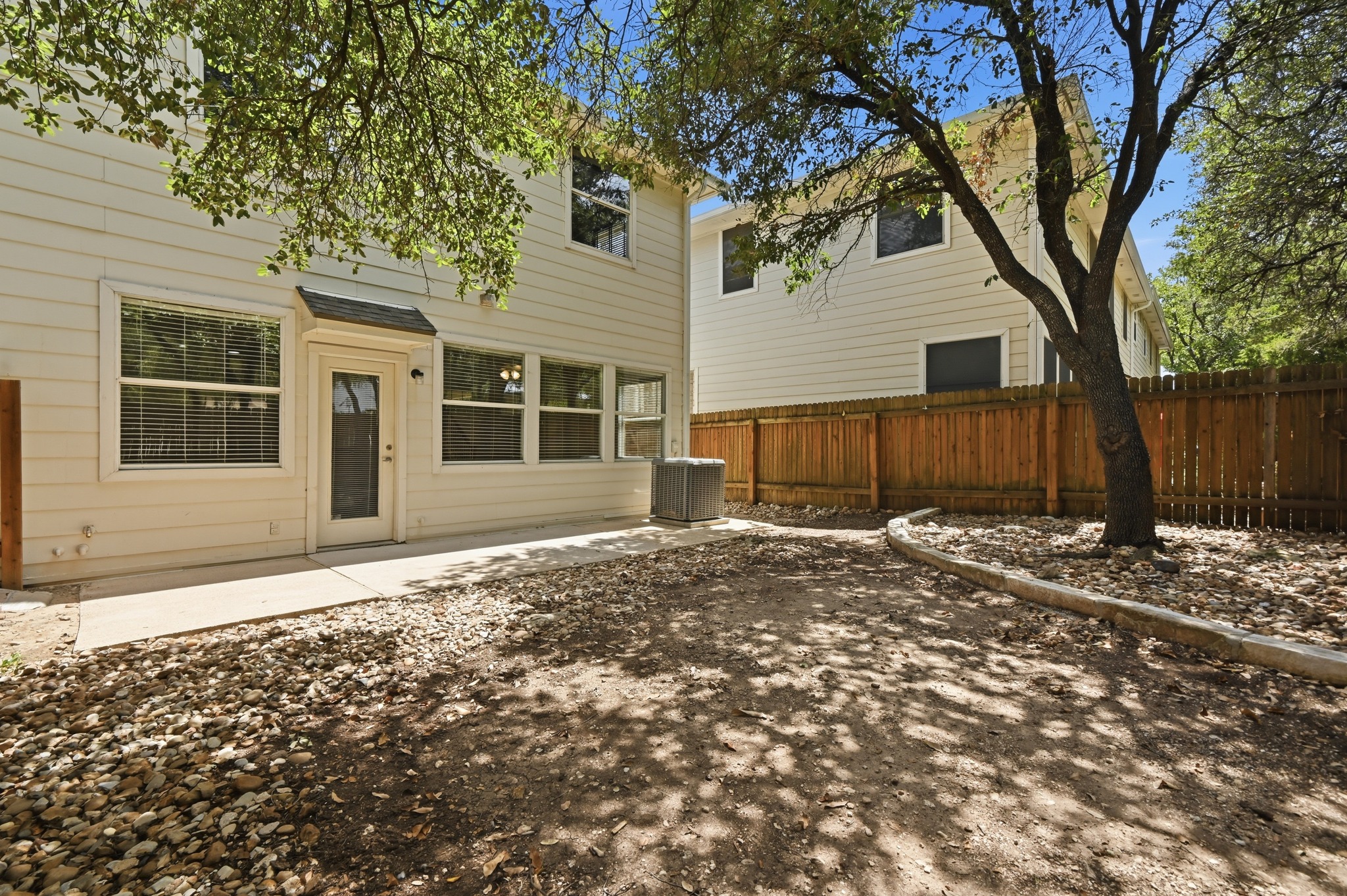 4508 Duval Road, Unit 4401 Austin, TX 78727 - Photo 21 of 26 Mature trees shade a private fenced backyard with a concrete patio slab.