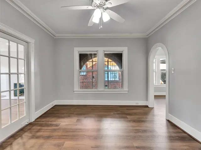 an empty room with wooden floor chandelier and windows