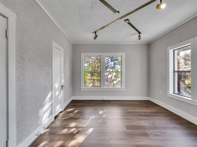 an empty room with wooden floor and windows