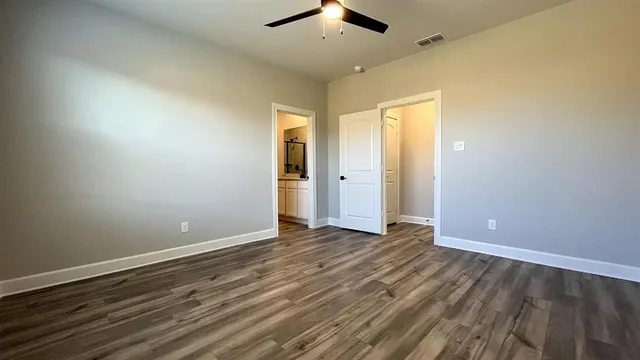 an empty room with wooden floor chandelier fan and windows