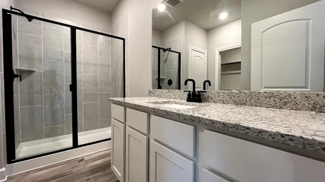 a bathroom with a granite countertop bathtub shower sink vanity and toilet