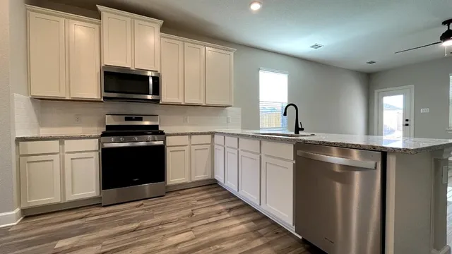 a kitchen with stainless steel appliances granite countertop a stove a refrigerator and a cabinets