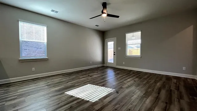 a view of an empty room with wooden floor and a window