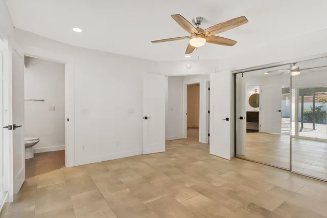 an empty room with closet and a ceiling fan