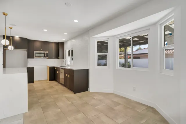 a dining room with furniture a potted plant and kitchen view