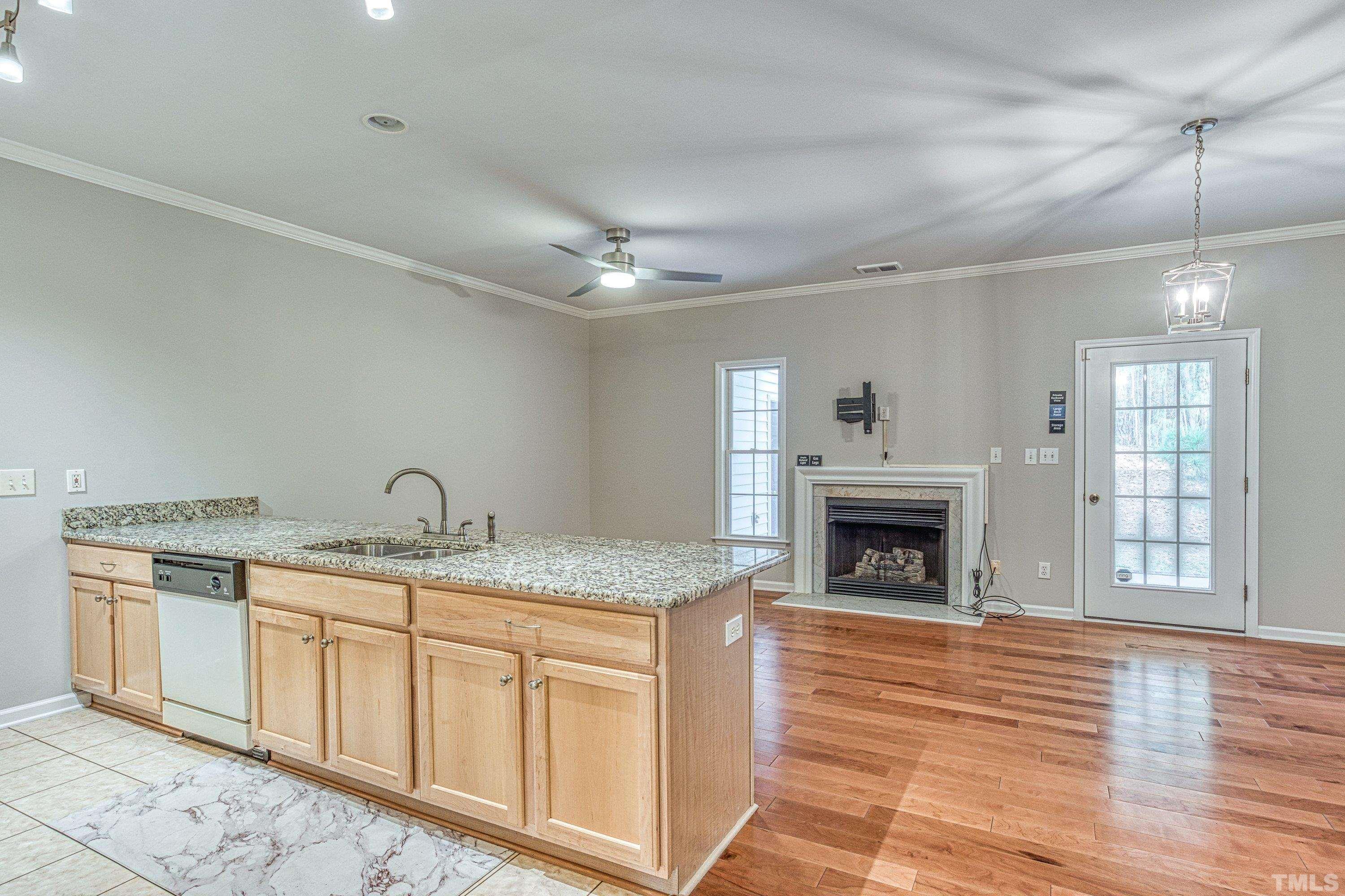 3045 Coxindale Drive Raleigh, NC 27615 - Photo 12 of 42 a hall with kitchen island a sink wooden floor and a fireplace