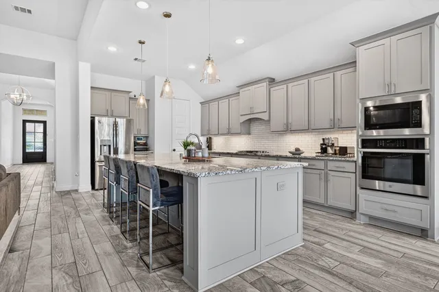 a kitchen with kitchen island granite countertop a sink cabinets and stainless steel appliances