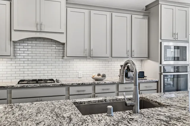 a kitchen with stainless steel appliances granite countertop a sink stove and cabinets