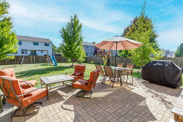 a view of a chairs and table in the back yard of a house
