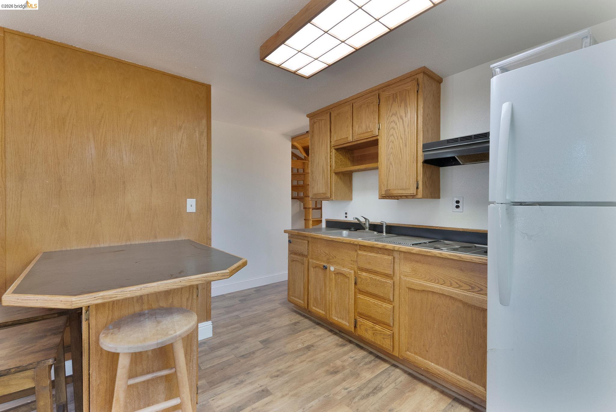 22963 Robertson Ranch Road Sonora, CA 95370 - Photo 60 of 90 Galley kitchen featuring wood cabinetry with ample storage, laminate countertops, stainless steel appliances, and wood-finish flooring throughout