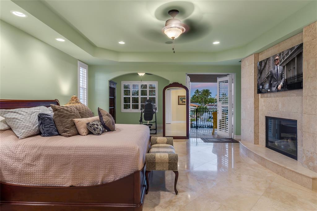 3489 Northeast 30th Avenue Lighthouse Point, FL 33064 - Photo 26 of 42 a bedroom with a large bed and a fireplace