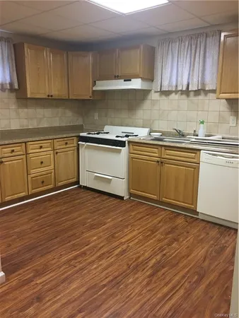a kitchen with granite countertop wooden floors appliances cabinets and a sink