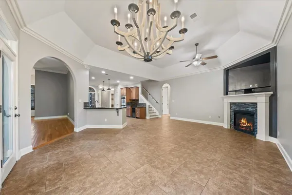 a view of a livingroom with a fireplace a chandelier and windows