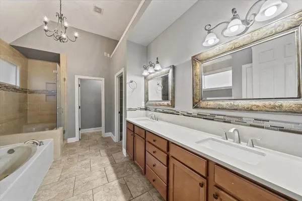 a spacious bathroom with a double vanity sink a large mirror and a bathtub
