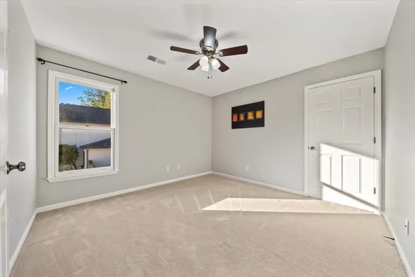 an empty room with windows and ceiling fan