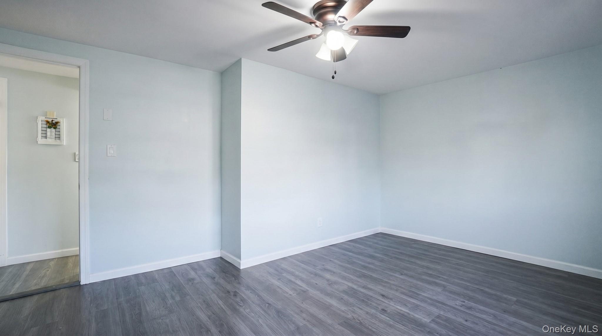 63 Blacksmith Road Levittown, NY 11756 - Photo 17 of 25 Spacious room featuring light-toned walls, wood-finish flooring, a ceiling fan with integrated lighting, and crisp white baseboards