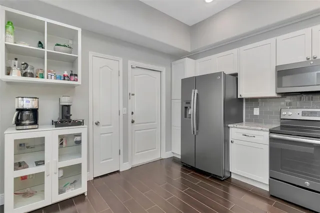 a kitchen with stainless steel appliances granite countertop a refrigerator a sink dishwasher a stove and white countertops with wooden floor