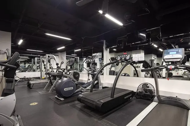 a living room with a black white checkered floor with a gaming machine and dining table