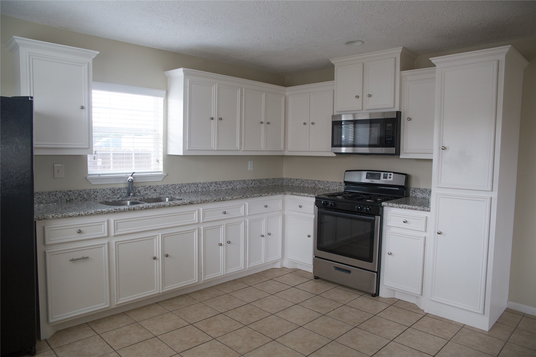 16947 Avenue A Channelview, TX 77530 - Photo 6 of 12 a kitchen with stainless steel appliances granite countertop white cabinets granite counter tops and a window