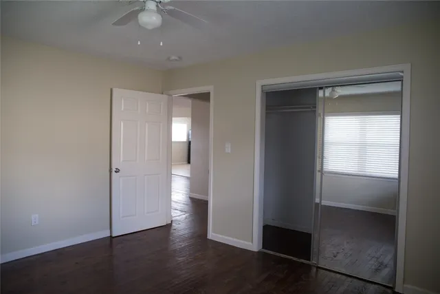 an empty room with wooden floor closet and windows