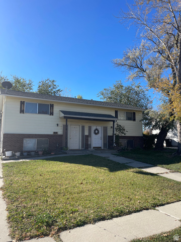 Split foyer home with brick siding and a front yard