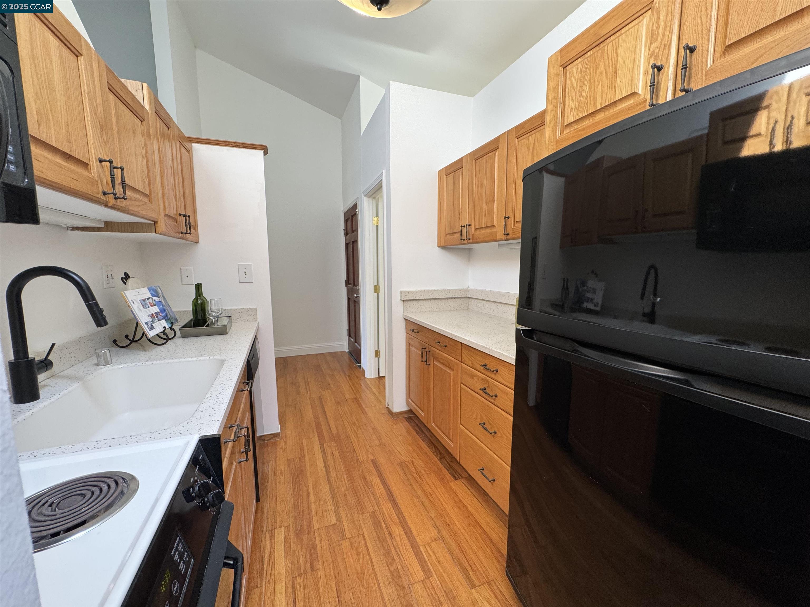 2075 Ascot Drive, Unit 221 Moraga, CA 94556 - Photo 11 of 21 a kitchen with stainless steel appliances a sink a stove wooden floor cabinets and a dining table