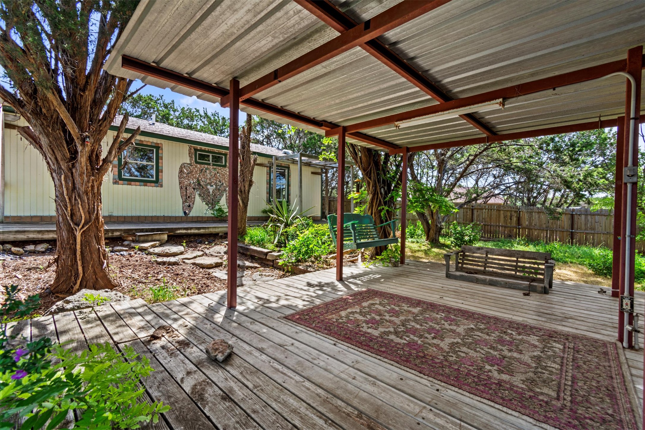 6 El Sol Road Wimberley, TX 78676 - Photo 18 of 20 A relaxed covered deck offers ample space for outdoor enjoyment and verdant landscaping.
