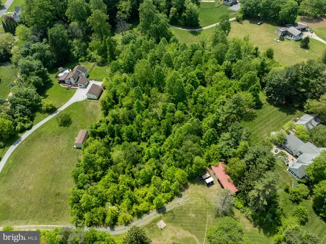 an aerial view of residential houses with outdoor space and trees all around