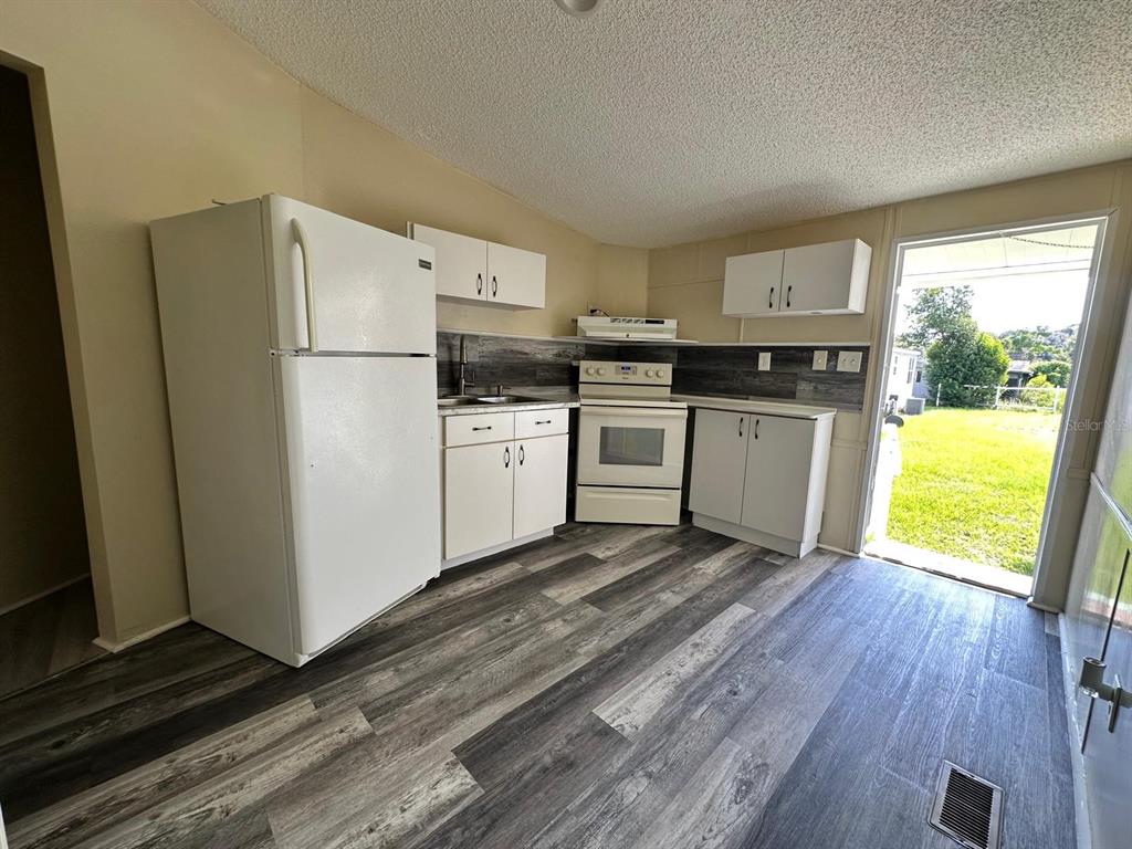 5920 Southwest 62nd Place Ocala, FL 34474 - Photo 18 of 20 a kitchen with stainless steel appliances a refrigerator sink and wooden floor