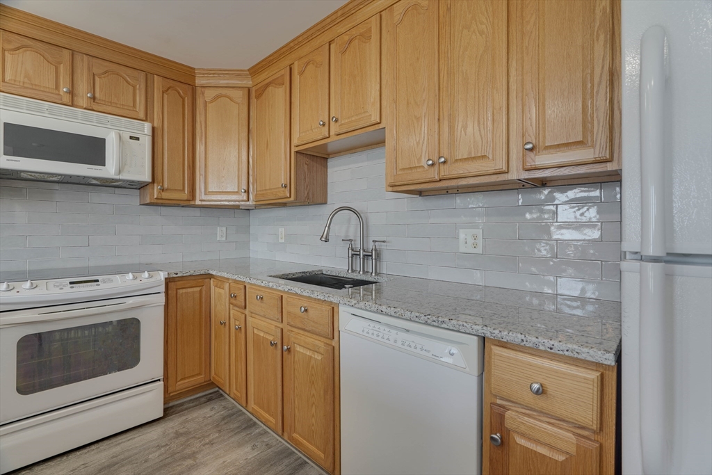 168 Humphrey Street, Unit 2 Swampscott, MA 01907 - Photo 2 of 26 a kitchen with stainless steel appliances granite countertop a sink dishwasher a stove and a microwave oven with cabinets