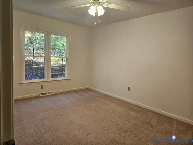 an empty room with a chandelier fan and windows