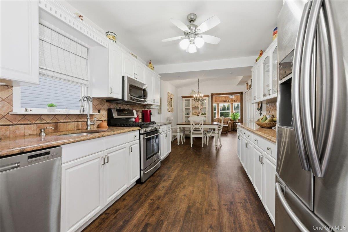 80 Newport Road Island Park, NY 11558 - Photo 8 of 26 a large kitchen with stainless steel appliances granite countertop a refrigerator a sink dishwasher a stove and white countertops with wooden floor